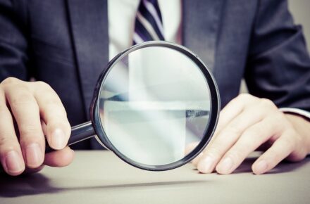 虫眼鏡を持つスーツの男性